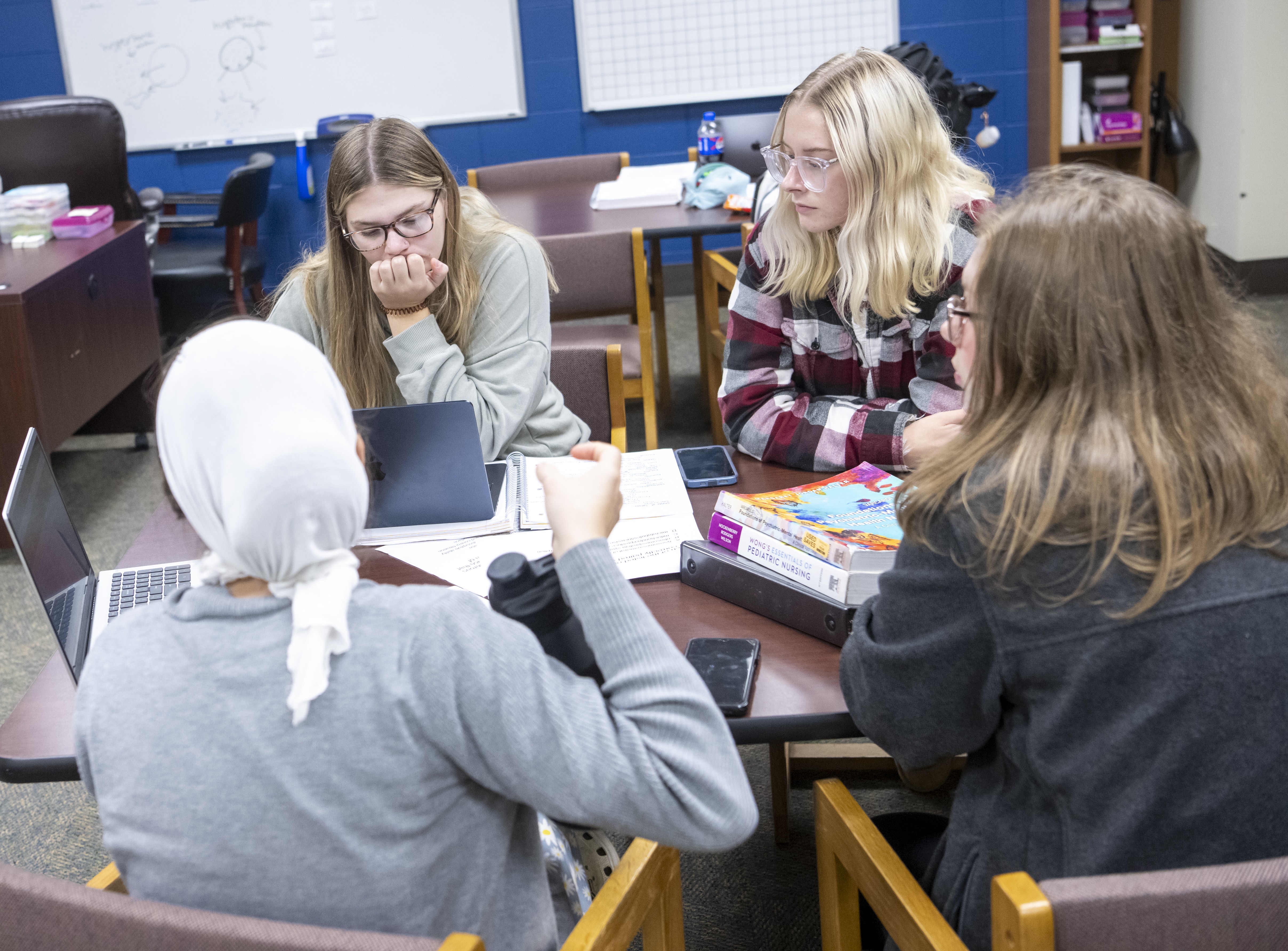 Four students sitting in the learning center studying together.