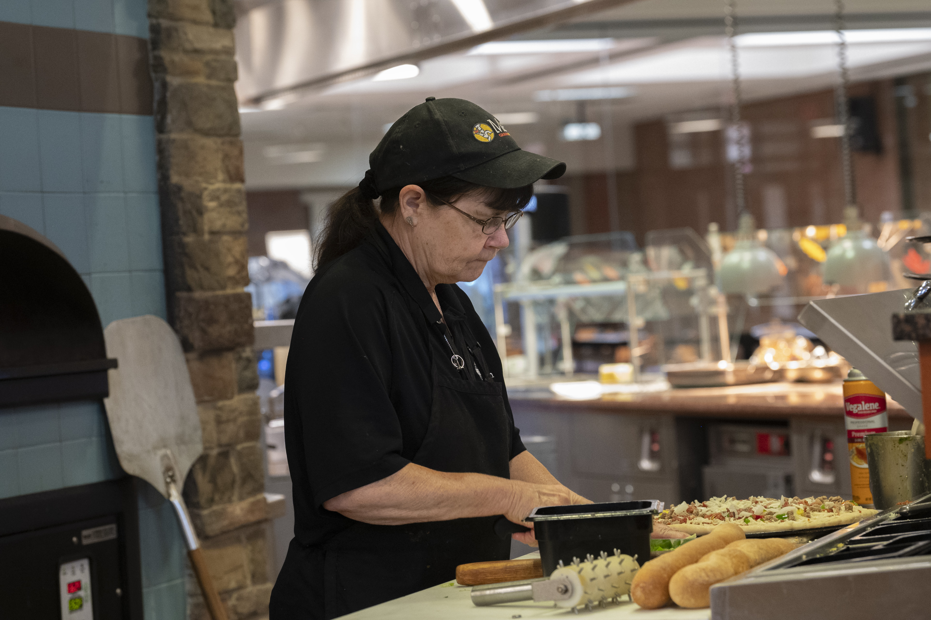 A Metz worker is preparing a pizza.